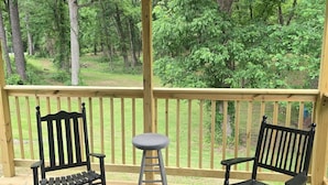 A covered outdoor area with two wooden chairs, a small stool, and a ceiling fan.
