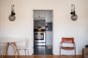 A modern kitchen with white cabinets, a stainless steel oven, and a hanging light fixture.