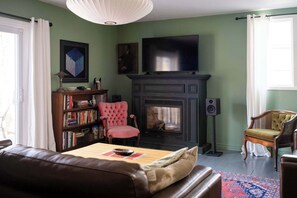 A living room with a fireplace, a television, a bookshelf, and a red armchair.