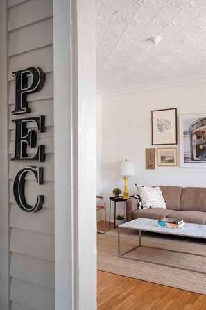 Un salon avec un canapé, une table basse, une lampe et des tableaux encadrés accrochés au mur.