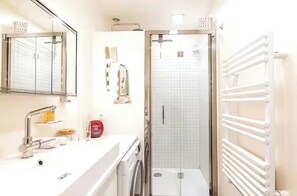 Ein modernes Badezimmer mit Dusche, Waschbecken und Spiegel.