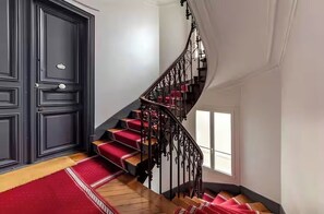 Eine prächtige Treppe mit roten Teppichstufen und einem schwarzen Metallgeländer.