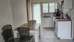 Una cucina moderna con mobili bianchi, un piano di lavoro in legno e un'area pranzo con tavolo e sedie.