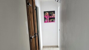 Un corridoio con porte in legno, pavimento piastrellato e condizionatore d'aria a muro.