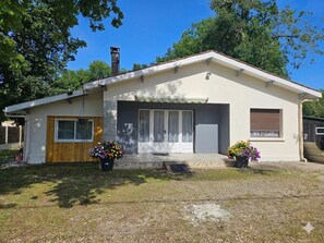 A single-story house with a front door, a garage door, and a small porch area with potted plants.