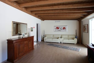 Un soggiorno con soffitto in legno, un ampio specchio, un divano bianco e un tappeto.