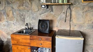 A kitchenette with a wooden cabinet, a sink, a small refrigerator, and a stone wall. - Casa Paz by Otium (La Cruz)