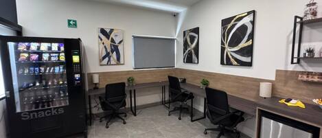 Una sala conferenze con una macchina distributrice, una lavagna e opere d'arte astratta alle pareti.