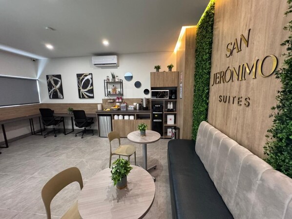 A modern office space with a reception area, a kitchenette, and a seating area with a sofa and tables.
