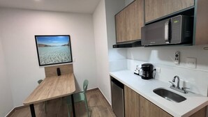 A compact kitchen with a dining area, a microwave, a coffee maker, and a dishwasher. - San Jeronimo Suites (Monterrey)