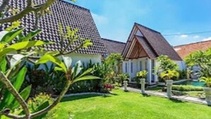 A residential property with a well-maintained lawn, a house with a tiled roof, and a garden with various plants. - Cozzy  White House Villa Bali (Badung)