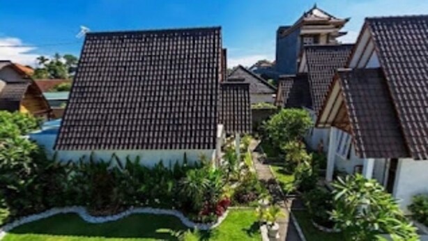 A traditional Japanese-style building with a tiled roof, surrounded by a well-maintained garden with various plants and a pathway. - Cozzy  White House Villa Bali (Badung)