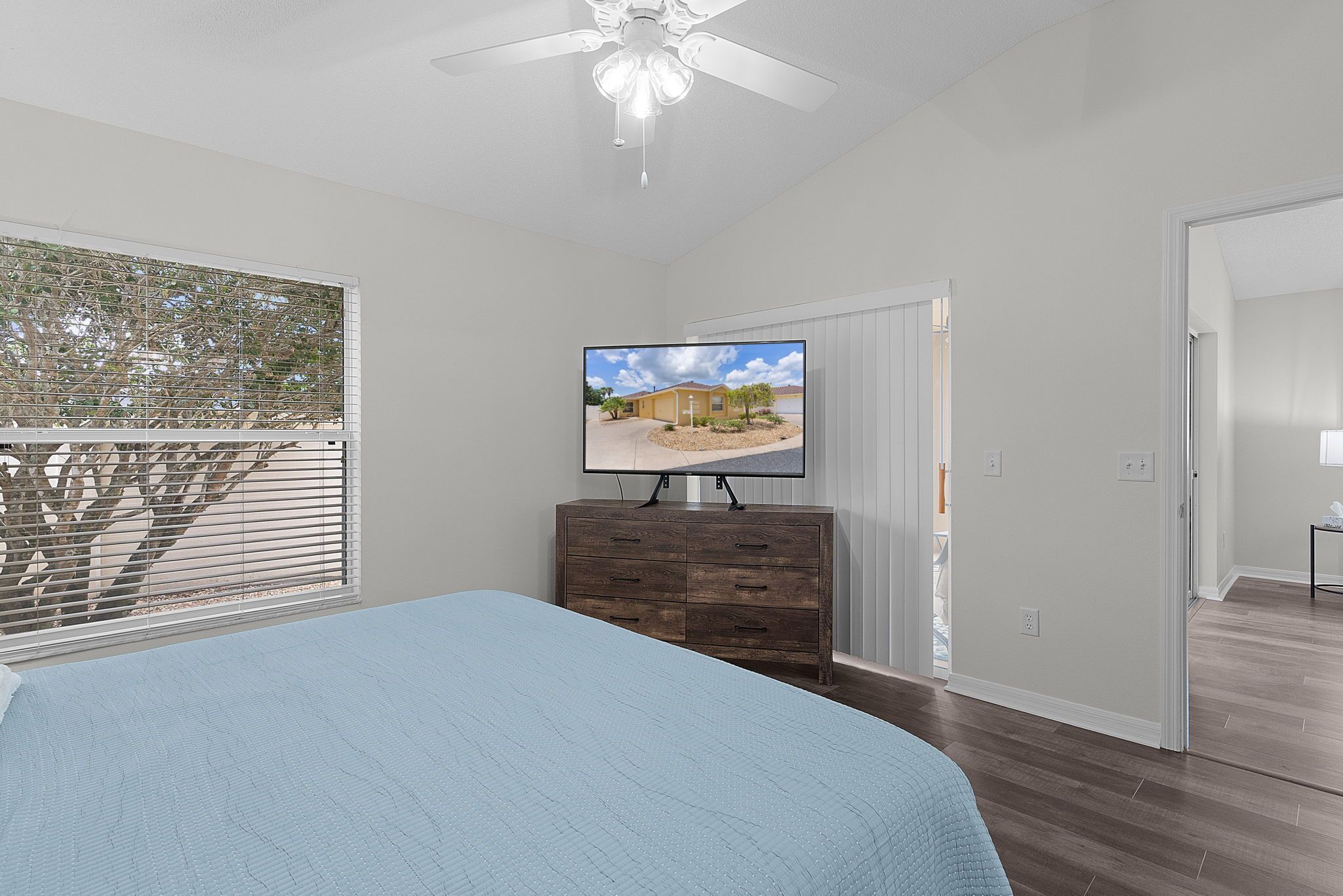 A bedroom with a bed, a dresser, a television, and a ceiling fan.