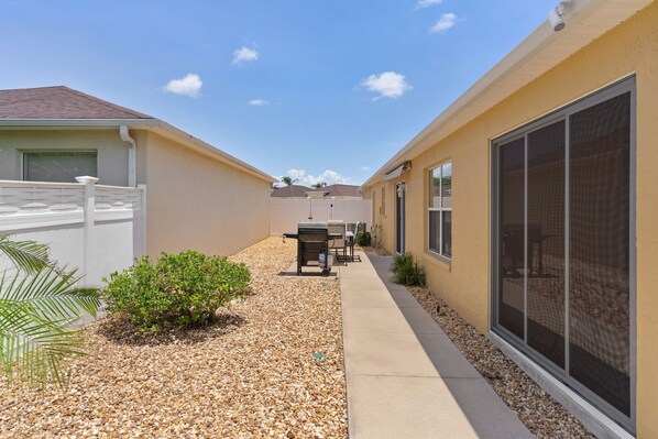 A residential area with a pathway, a grill, and a screened porch. - Updated 3/2 Bonnybrook Home - Pet Friendly, Fenced Yard (The Villages)