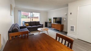 Un salon comprenant un canapé, un téléviseur, un meuble en bois et une table à manger.