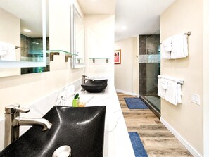 Un bagno moderno con un lavandino nero, uno specchio grande e un box doccia in vetro.