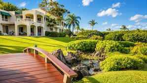 A wooden bridge over a pond, a well-maintained lawn, and a building with a balcony. - Villa, Garden View, 2-bedroom (Kihei)