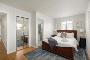 Ein Hotelzimmer mit einem großen Bett, einem begehbaren Kleiderschrank, einem Badezimmer mit Dusche und einem Fenster mit Jalousien.