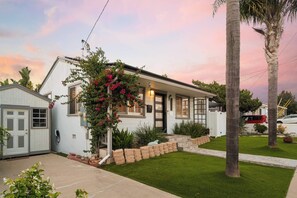 Ein eingeschossiges Haus mit Veranda, einer kleinen angebauten Garage und einem gepflegten Rasen.