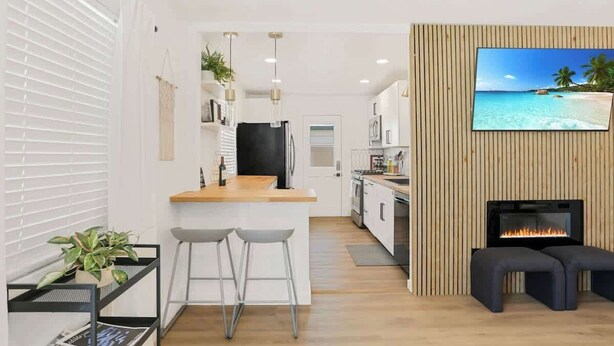 Una cocina moderna con una isla de madera, taburetes de bar y un televisor fijado a una pared de madera.