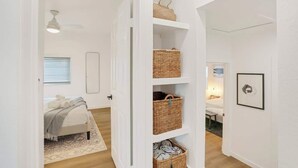 Un pasillo con una cama, una puerta blanca y un estante con cestas.