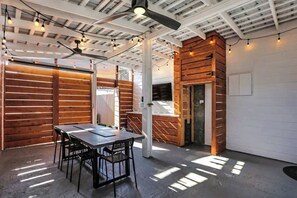 Ein modernes Interieur mit freiliegenden Decken, Holzwandverkleidung, einer Essecke mit Tisch und Stühlen sowie einem Kamin.