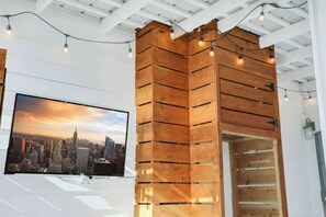 Ein Zimmer mit einer Holzwand, einem montierten Fernseher, der eine Stadtansicht zeigt, und Lichterketten.