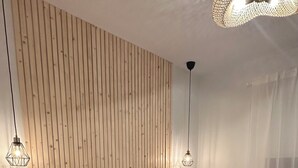 A modern bedroom with a wooden slat wall, a bed with a brown throw blanket, and two pendant lights. - Junior suite double with breakfast - Casa Regina Tenerife with terrace and Pool (Tamaimo)