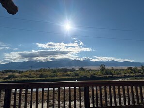 A wooden deck overlooking a landscape with mountains, trees, and a clear sky.