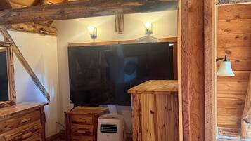 Une pièce rustique en bois, avec un plafond en pente, un lit, un petit radiateur et une table en bois.
