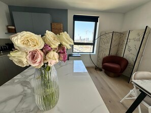 Eine moderne Küche mit Marmorarbeitsplatte, einer Blumenvase und Blick auf die Stadt durch ein Fenster.