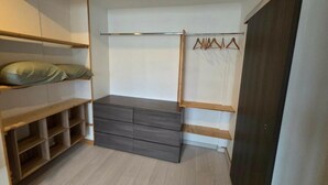 A walk-in closet with wooden shelves, a grey dresser, and a clothing rack. - Apartment T3 of 83 M2 in Mâcon (Mâcon)