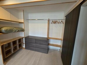 Un vestidor con estantes de madera, un aparador gris y un perchero.