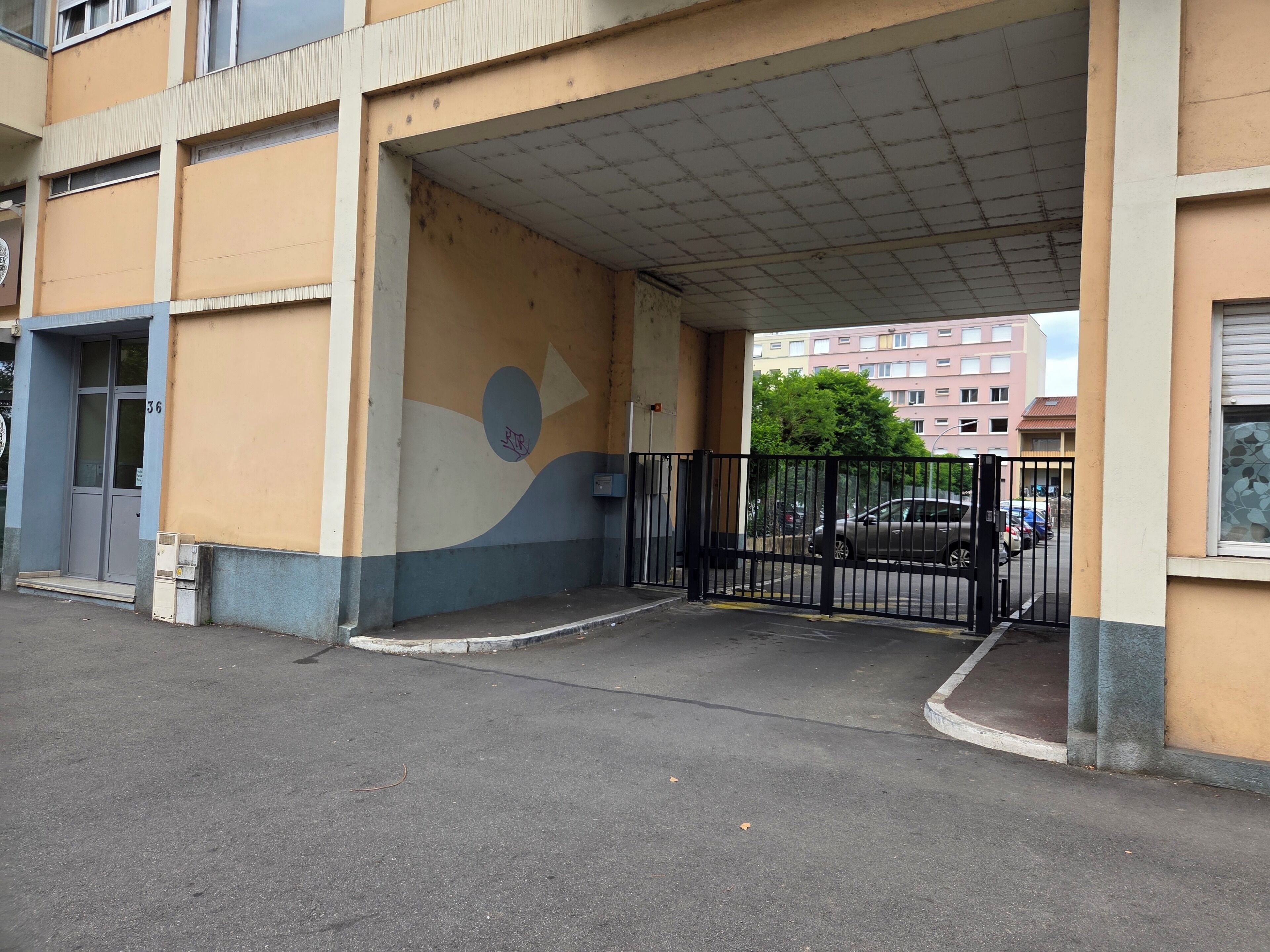 Een gebouwtoegang met een overdekte doorgang, een poort en een parkeerplaats.