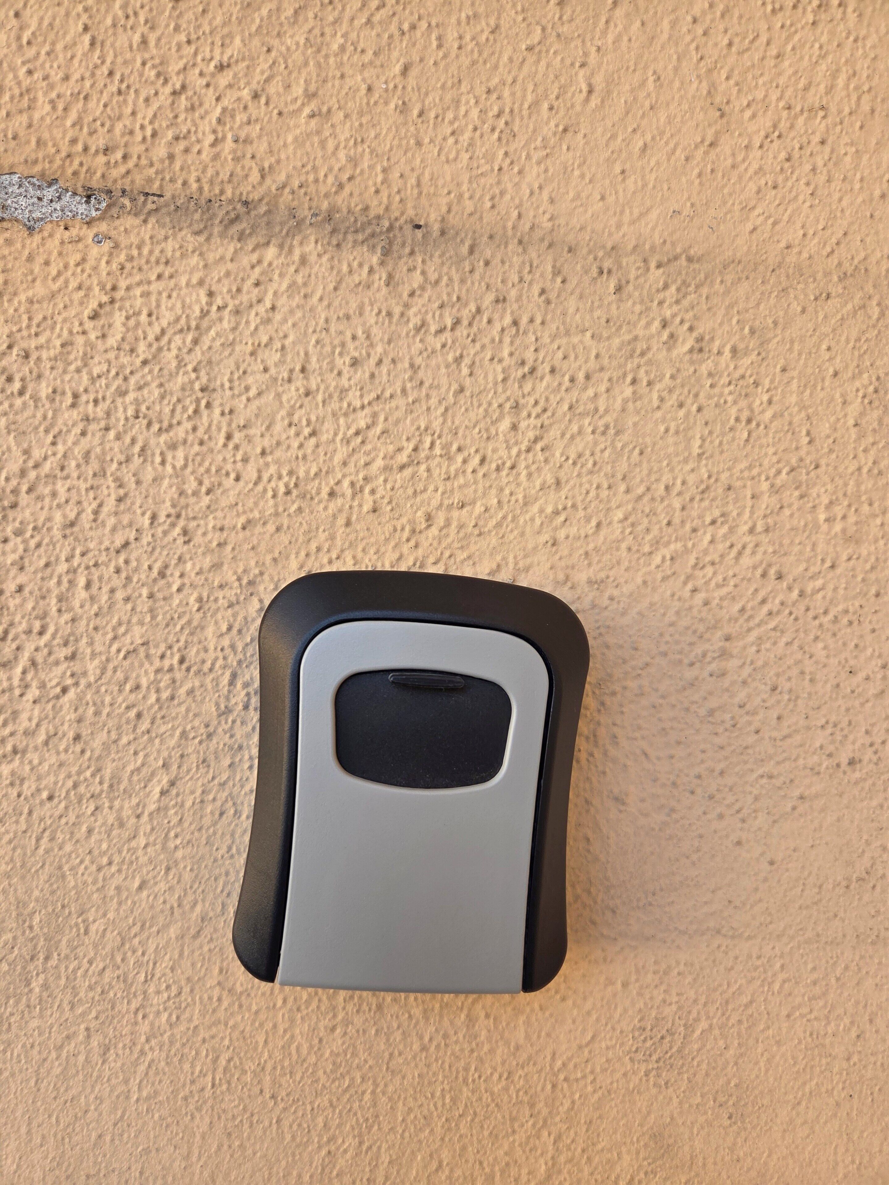 Un objet fixé au mur, de forme rectangulaire, avec une partie supérieure noire.