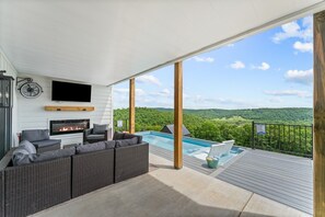 Ein überdachter Außenbereich mit Pool, Sitzgelegenheiten und Kamin.