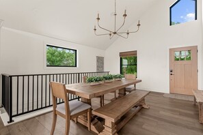 Un comedor con una mesa de madera, sillas, un banco y una araña.