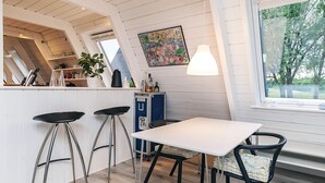 A kitchen with a white table, bar stools, a blue cabinet, and a window with a view of trees. - 4 Star Holiday Home in Farso (Farso)