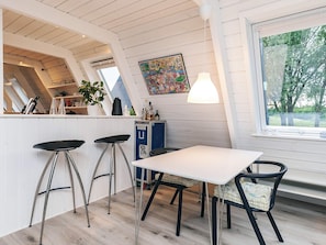 A kitchen with a white table, bar stools, a blue cabinet, and a window with a view of trees. - 4 Star Holiday Home in Farso (Farso)