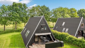 Two modern, triangular-roofed buildings with outdoor decks, surrounded by lush greenery. - 4 Star Holiday Home in Farso (Farso)