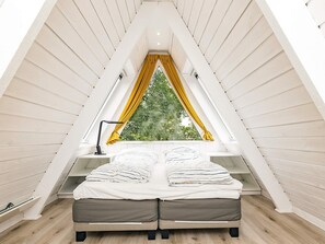 A triangular attic bedroom with a bed, a desk, and a window with yellow curtains. - 4 Star Holiday Home in Farso (Farso)