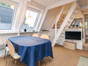 Un espace repas comprenant une table, des chaises, un téléviseur et un escalier.