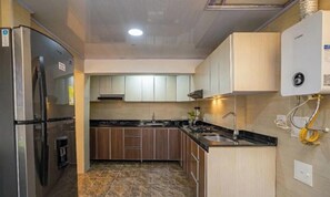 Eine Küche mit Kühlschrank, Herd, Spüle und Boiler.