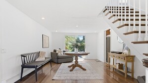Un salon moderne avec un plancher en bois, une table ronde, un canapé et un escalier.