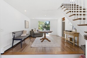 Ein modernes Wohnzimmer mit Holzboden, einem runden Tisch, einer Couch und einer Treppe.