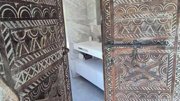 Une pièce comprenant un lit, une porte en bois ornée de sculptures complexes et un mur en marbre.