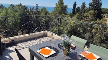 Un espace de restauration en plein air avec une table dressée pour deux personnes, entouré de verdure et offrant une vue panoramique.