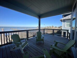 Eine Holzterrasse mit Stühlen und Blick auf das Meer und den Pier.