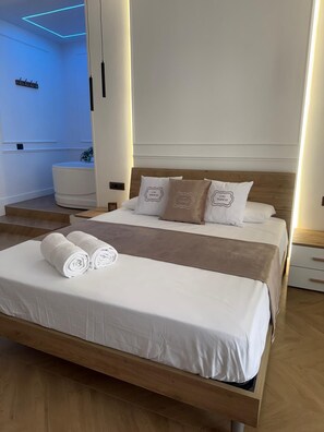 A modern hotel room with a wooden bed, white bedding, and a blue-lit ceiling. - Suites between Naples and Sorrento (Torre del Greco)