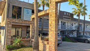 A hotel with a stone facade, a visible entrance, and a staircase leading to the parking area. - Hotel Palmas Quintero (Playas de Rosarito)